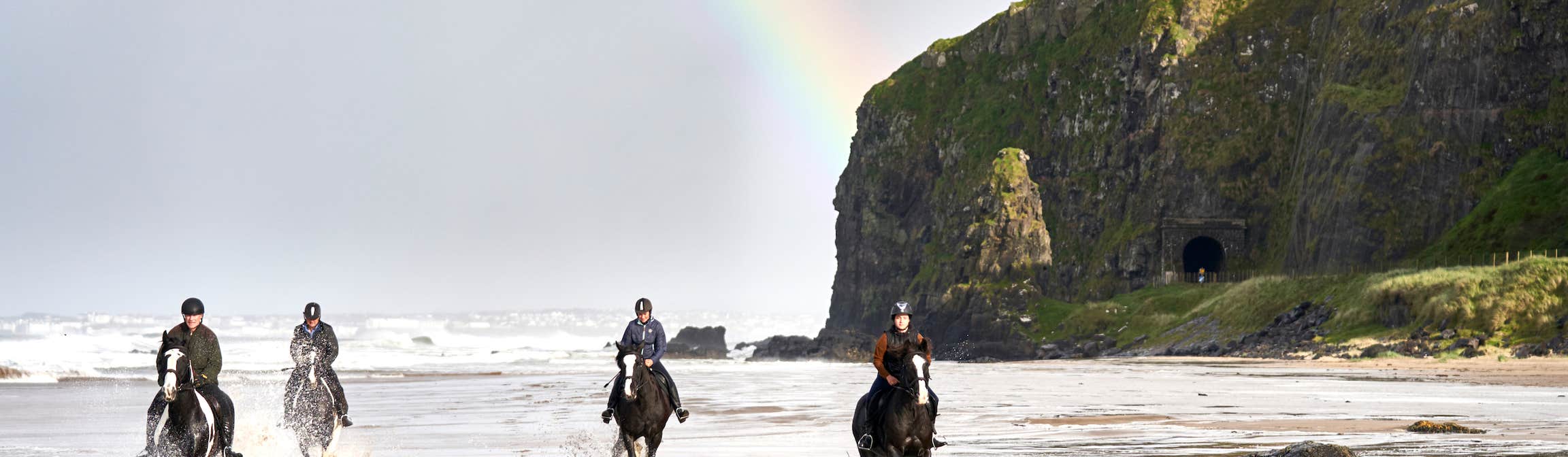Group riding horses on Downhill Beach in Cork.