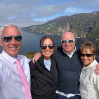 Four people wearing sunglasses pose for a selfie at the Cliffs of Moher
