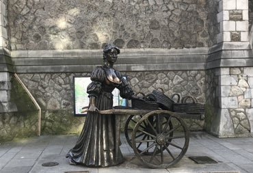 Bronze statue on a street of a lady holding a wheelbarrow