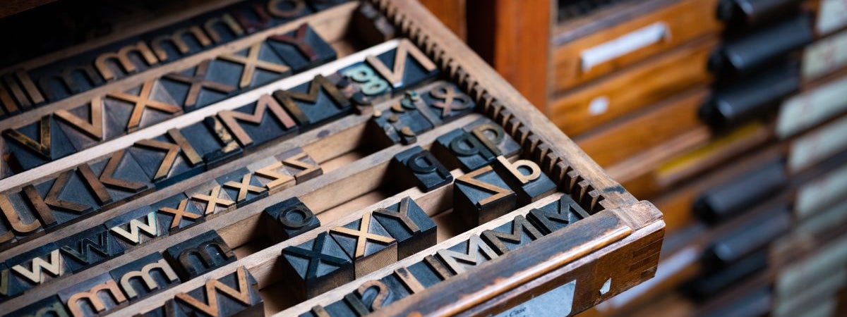 A case of wooden type partially pulled out of a type cabinet.