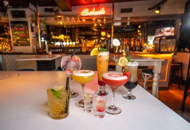 Selection of cocktails on a white table with a bar in the background