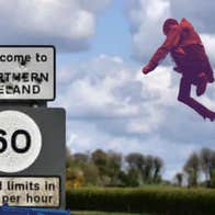 Beyond The Border – MAD Youth Theatre, A person dressed in dark red leaping up in the sky beside a road sign