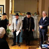4 people standing in front of a fireplace performing to an audience