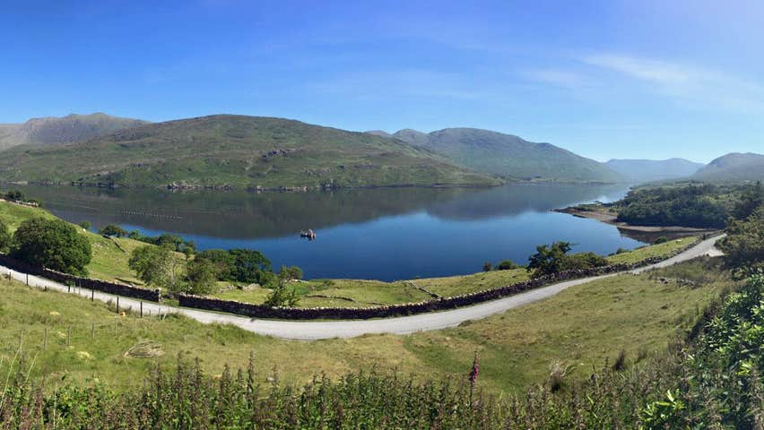 A view of killary fjord with mountains in background and green fields in the foreground