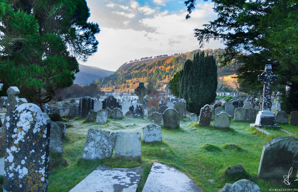 Ancient gravestones with overgrown grass in an old cemetery in Wicklow.