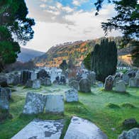 Ancient gravestones with overgrown grass in an old cemetery in Wicklow.