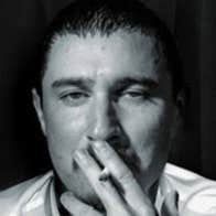 Comedian and actor Tom Rosenthal - headshot of man with half closed eyes and a cigarette up to his mouth