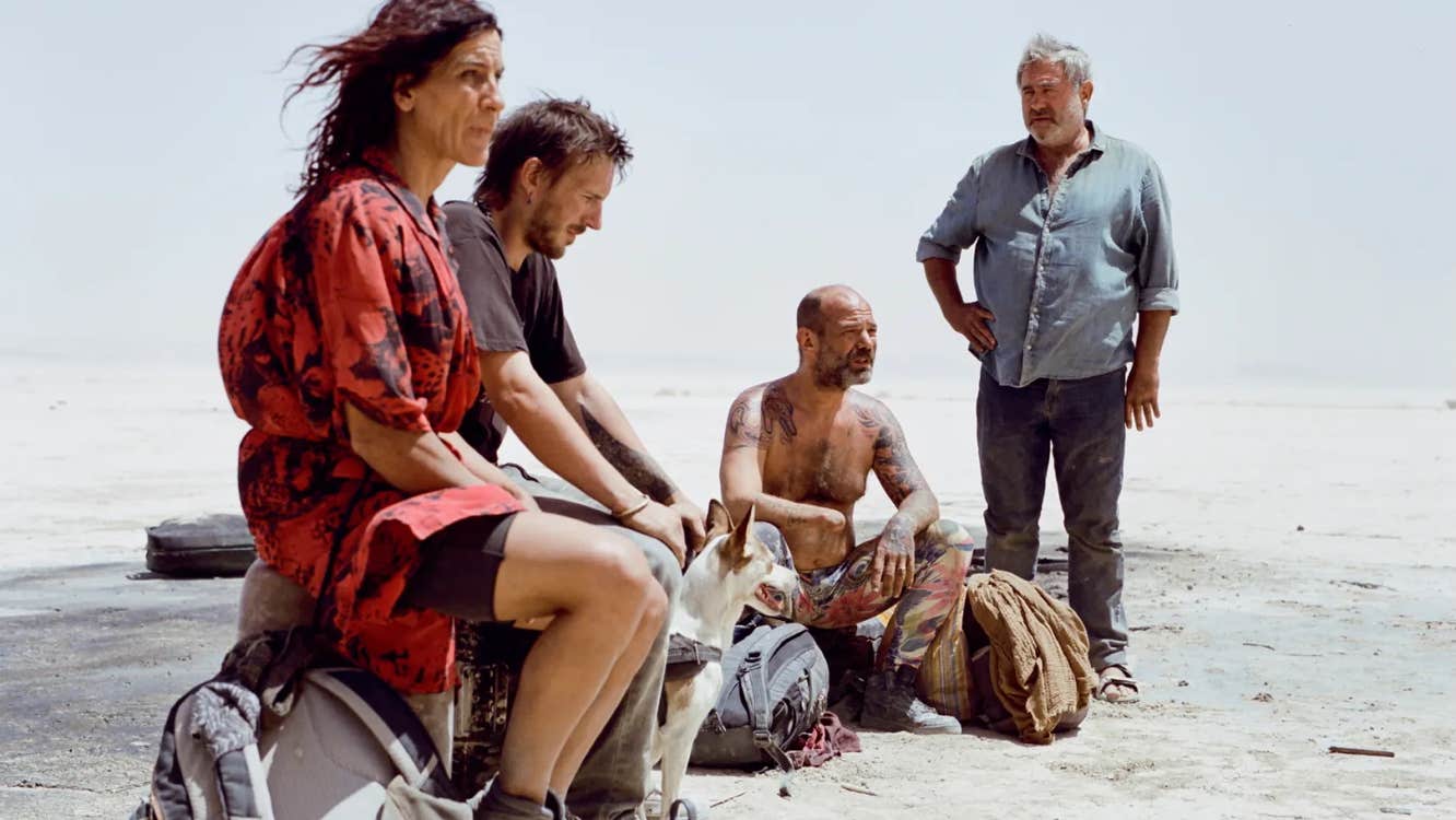 Three men and a woman in a desert.