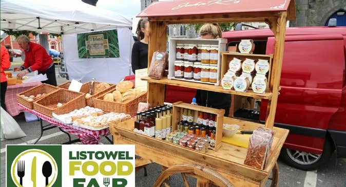 Listowel Food Fair 2025 - A wooden cart holding displays of various potted sauces beside table with wicker baskets containing different baked goods and loaves of bread.