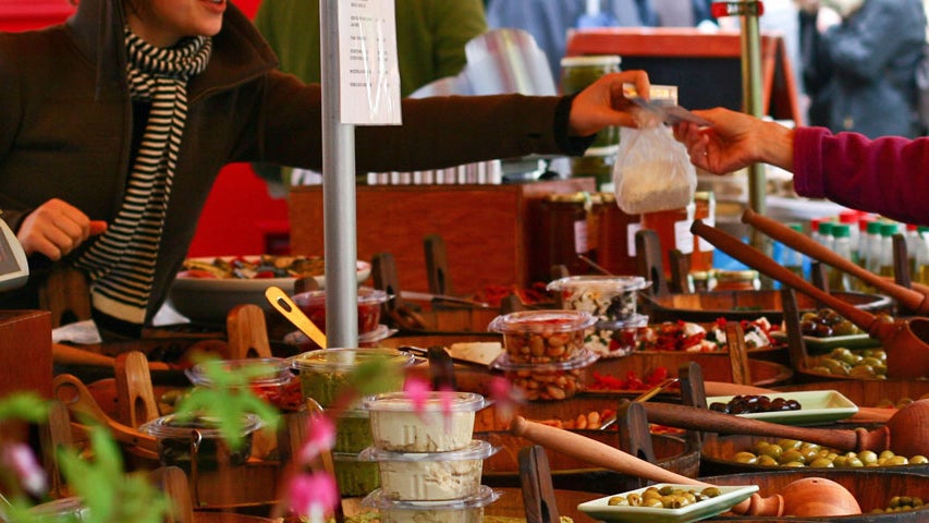 A display of olives in tubs with ladles and other fresh food at the Temple Bar Food Market