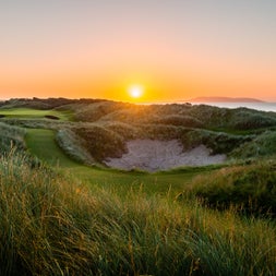 Sunset over golf course bunker with grass to the forefront