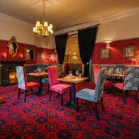 Elegant restaurant dining room with Georgian décor ornate mirrors patterned carpet and warmly lit tables