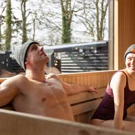 Two people wearing beanie hats sitting in a sauna