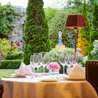 A set table with wine glasses next to a window overlooking a garden
