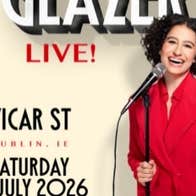 A laughing woman in red jacket holding a mic on a stand