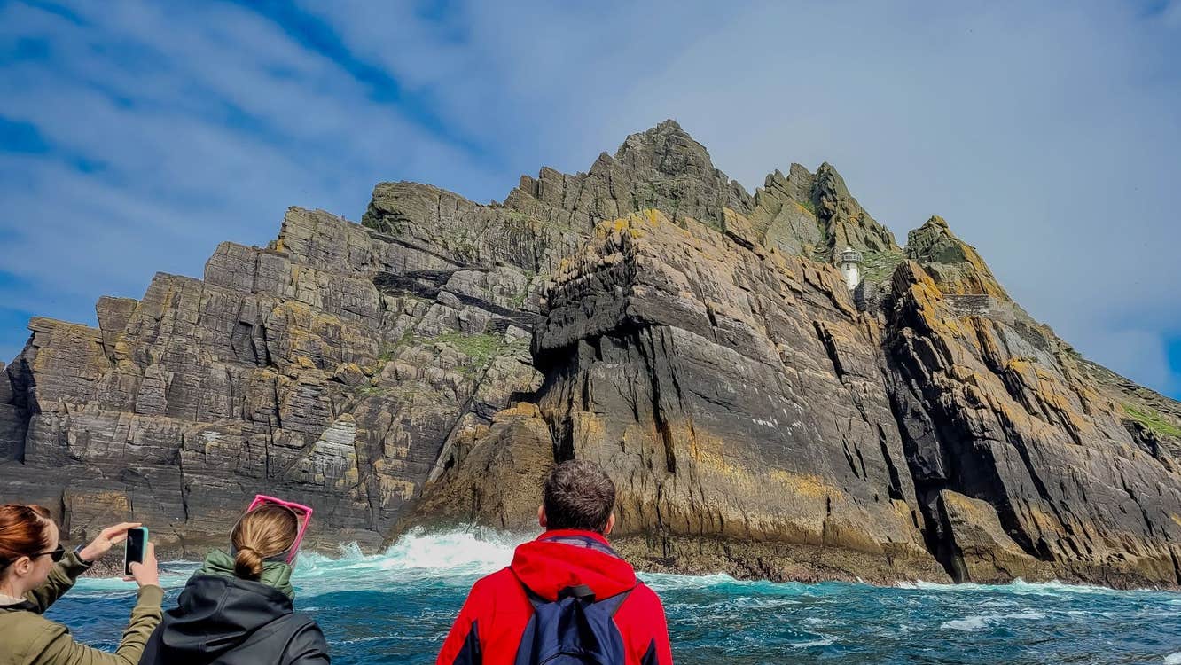 Three people on a boat taking photos of the Skellig Islands