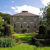 The exterior of a house at Kilmokea Country Manor Gardens with trees on either side.