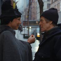 A man and a woman on a street, looking intimately into each other's eyes.