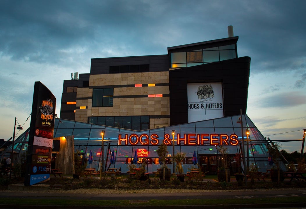 Glass exterior of a pub with the name displayed in neon lights