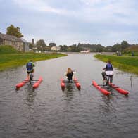 Three people cycling water bikes on a canal