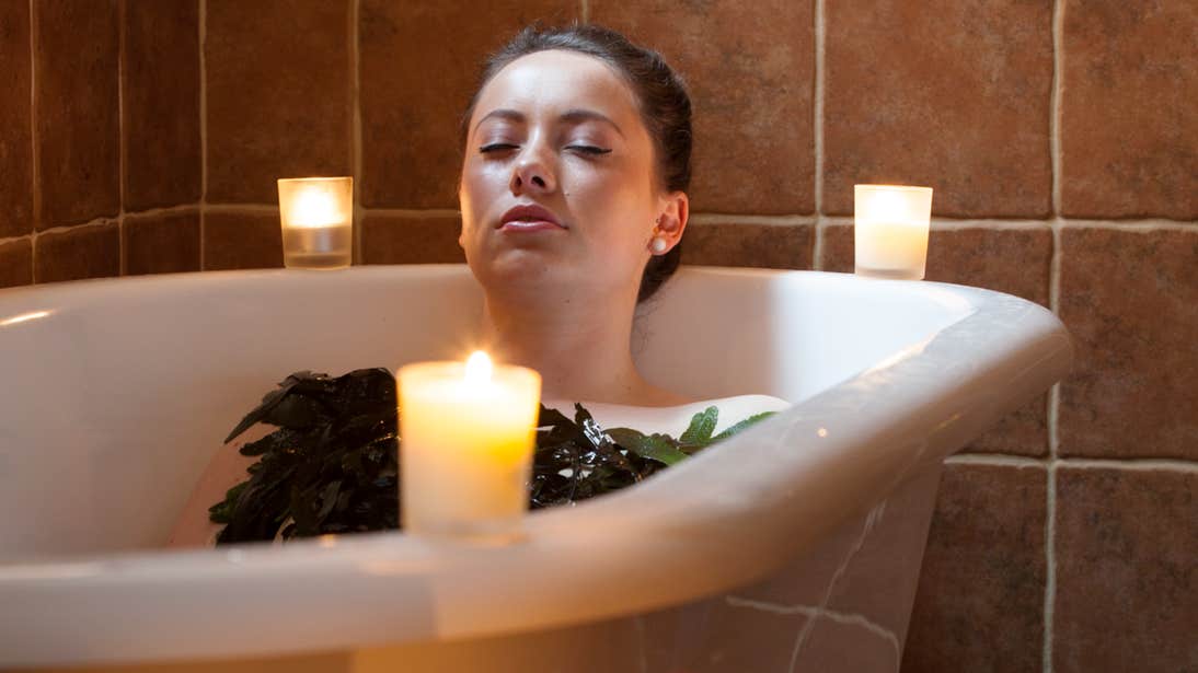 A woman relaxing in a seaweed candle-lit bath 