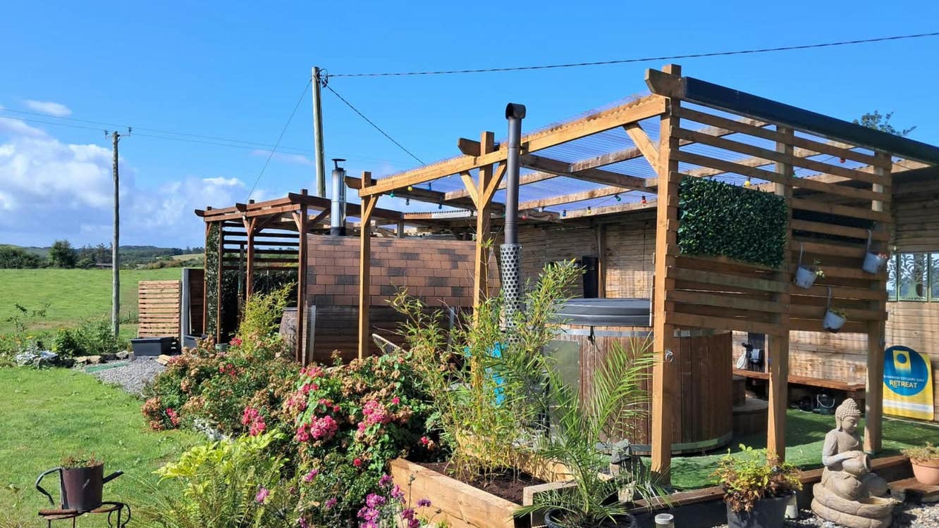 View of an outdoor hot tub and hydrotherapy tub housed within a timber wellness structure