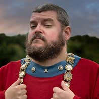 A tour guide in a red costume with decorative chain