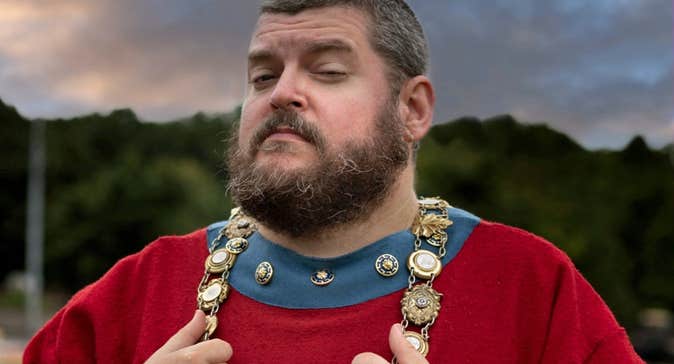 A tour guide in a red costume with decorative chain