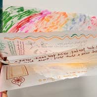 Silk Worm Families Drop-in: Ornamental Hangings - a hand holding a fan of drawings on thin white paper