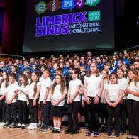 Large group of young children singing on a stage