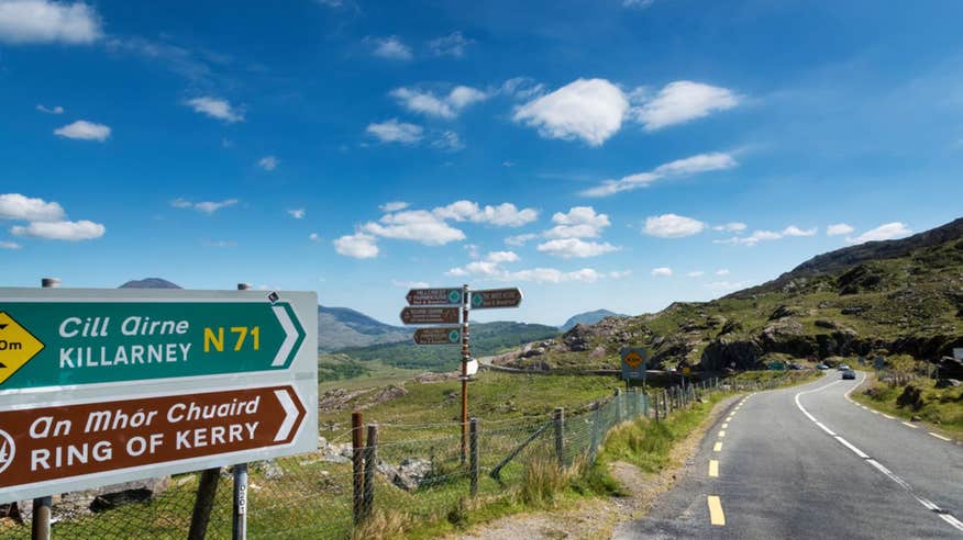 Signpost at the Ring of Kerry on a sunny day with hills in the distance