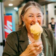 Lady holding an ice cream and cone while smiling at the camera