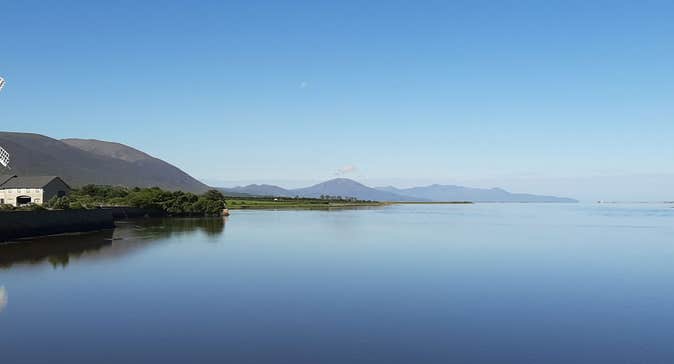 View of Blennerville Windmill overlooking the still waters of the harbour with mountains in the distance