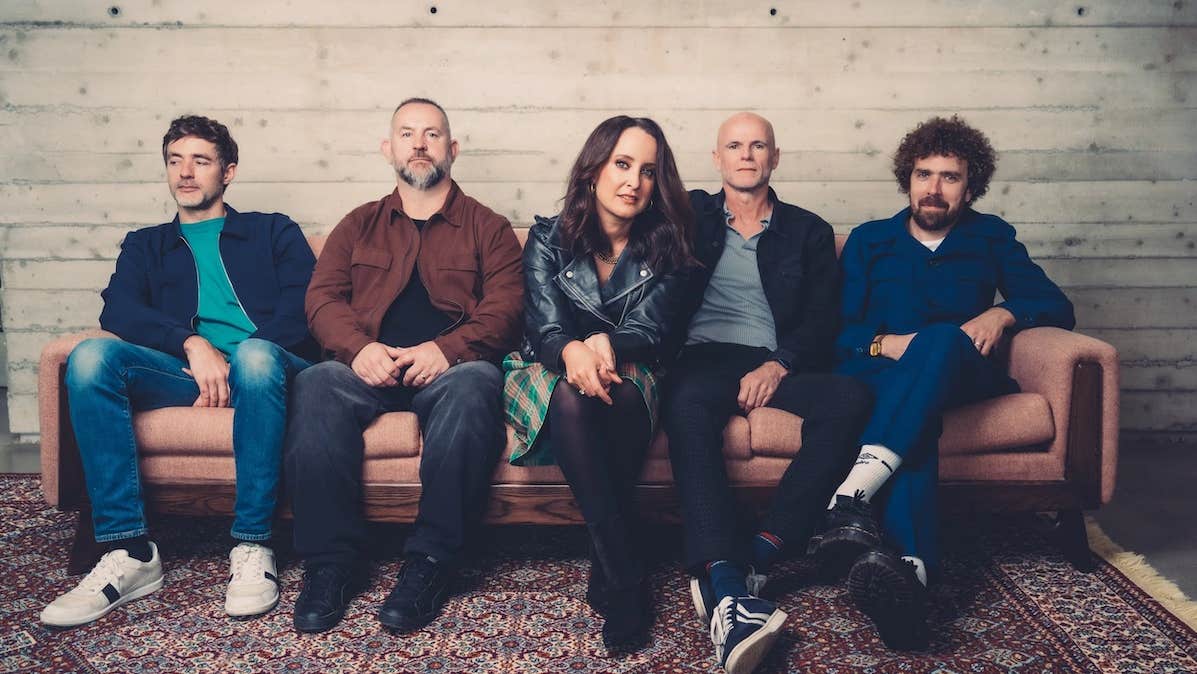 A group of 5 people sitting on a long sofa.