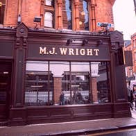 Exterior of a pub on a city street with the family name above the window