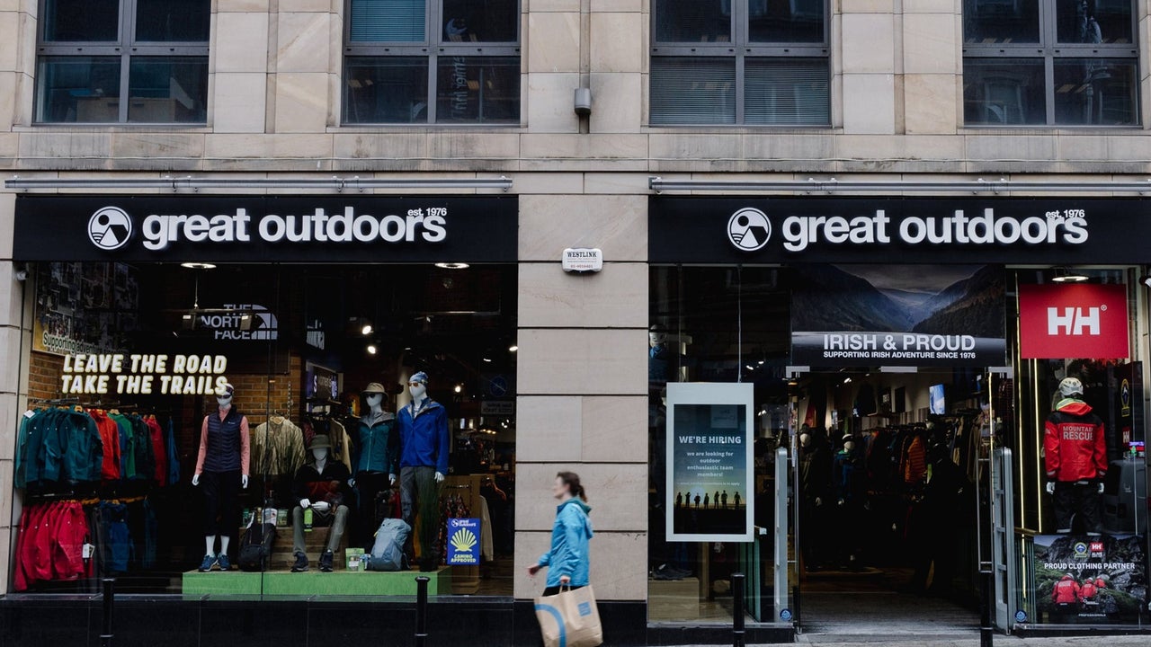 Shop front of a cream coloured building with black awning above the window and doors