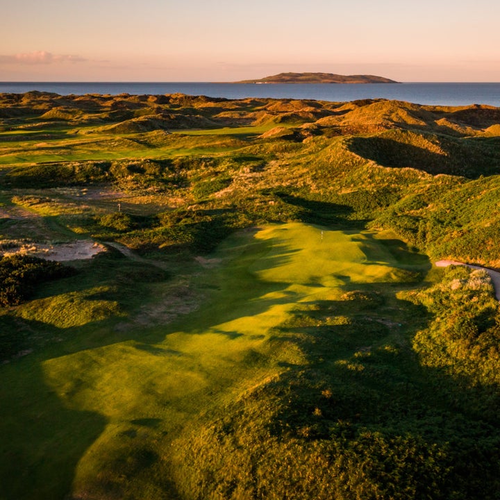 Aerial view of a golf green with the sea and an island in the background