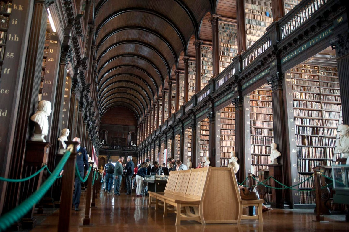 The long hall in Trinity College Library lined with memorial busts and benches.
