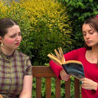 2 young women seated in a garden reading books