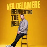A smirking man perched on a tall stool against plain dull yellow background.