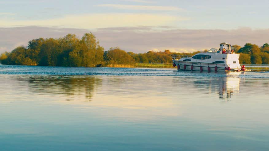 A boat cruising the River Shannon with views of trees nearby