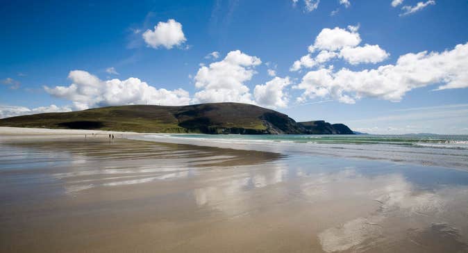Keel Beach, Achill Island with blue sky, fluffy clouds, and reflections on wet sand