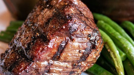 A cooked steak with green beans