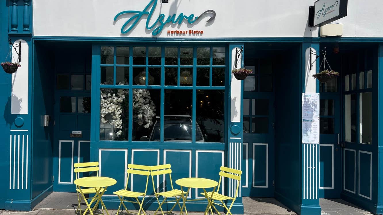 The exterior of a restaurant with green tables and chairs outside