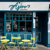 The exterior of a restaurant with green tables and chairs outside