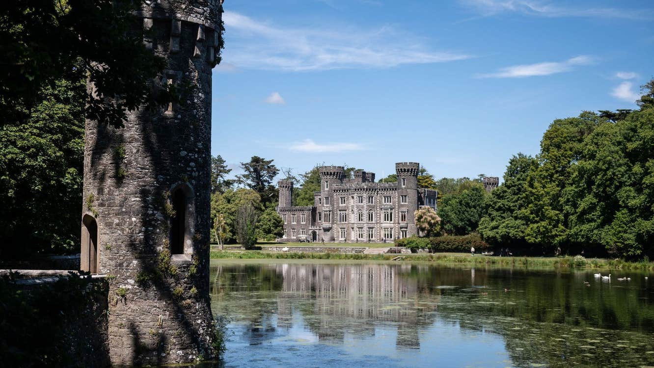 Johnstown Castle reflected in the lake surrounded by trees on the estate grounds