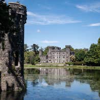 Johnstown Castle reflected in the lake surrounded by trees on the estate grounds