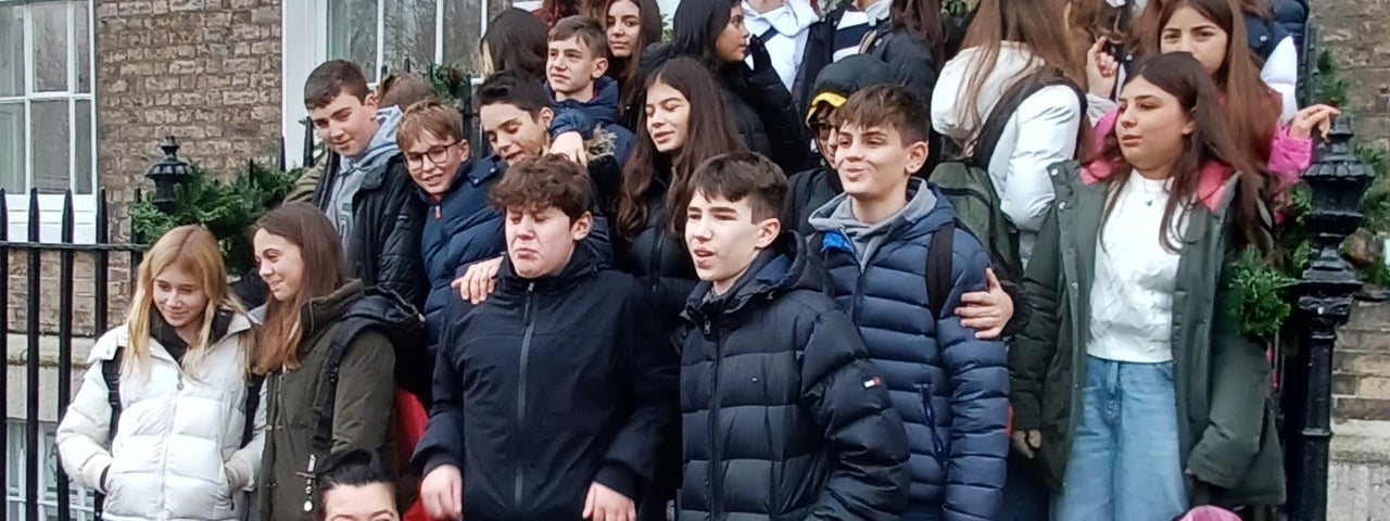 Group of teenagers and a tour guide posed on the steps of a Georgian house