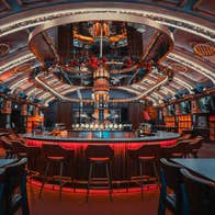 An illuminated circular bar featuring vaulted ceilings with architectural details