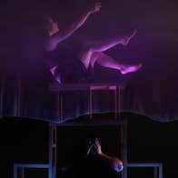 Darkly lit photo of person performing in contemporary circus